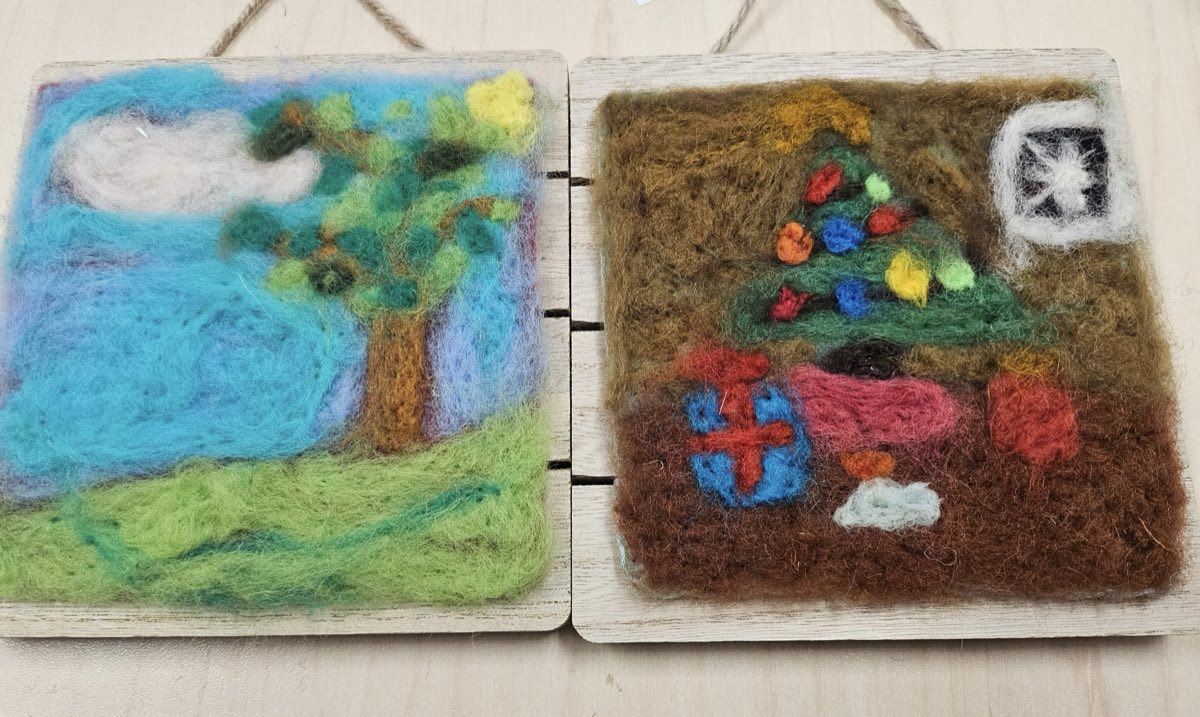 Two needle felted panels side by side: a spring scene with a leafy tree over green grass, and a winter scene with a decorated tree and wrapped presents on brown ground.